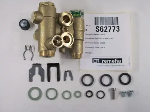 Hydraulikblock von Remeha, bestehend aus einem Hauptblock mit Anschlüssen, O-Ringen, Schrauben und Halterungselementen, angeordnet auf einem weißen Hintergrund.